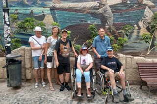 Tenerife - Groepsfoto bij muurschildering - Buitenhof Reizen begeleide vakanties voor mensen met een verstandelijke beperking.