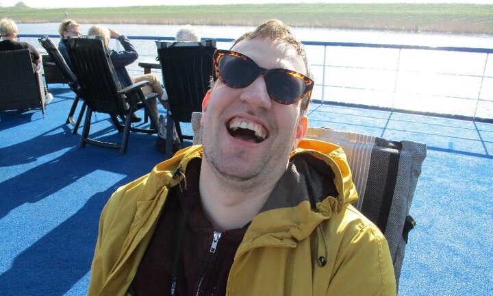 Bloemencruise-riviercruise- lachende man op dek-Buitenhof Reizen- begeleide vakanties voor mensen met een verstandelijke beperking