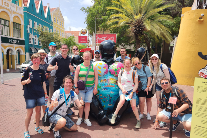 Buitenhof Reizen - Curacao - begeleide vakanties voor mensen met een beperking - Groepsfoto bij beeld van een vrouw met tekeningen