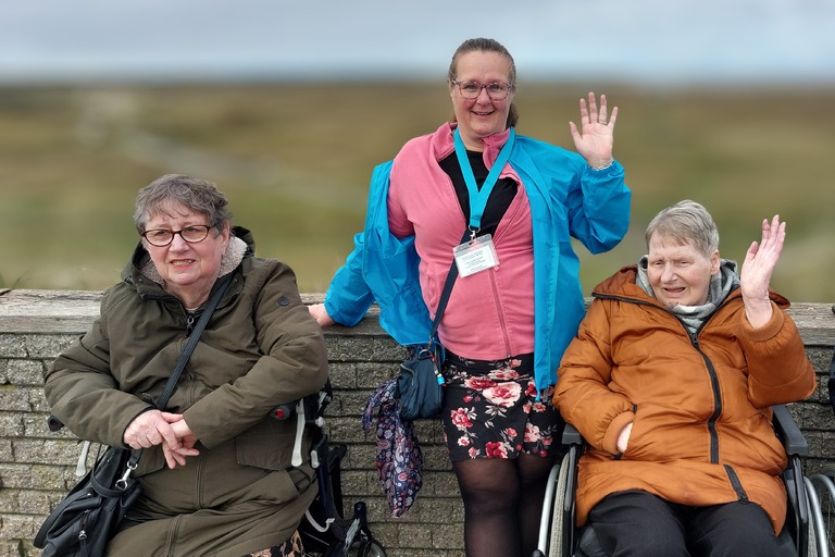 Buitenhof Reizen voor mensen met een verstandelijke beperking - Zorg - Zeehonden spotten op Texel - Begeleider met twee zwaaiende reizigers