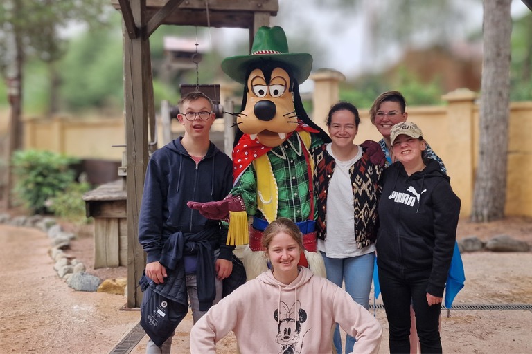 Buitenhof Reizen - Ondernemend - Disneyland kleine bus - begeleide groepsreizen met een verstandelijke beperking - lachende reizigers die met Goofy op de foto staan