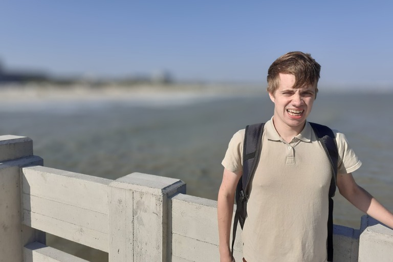 Buitenhof Reizen voor mensen met een verstandelijke beperking - Ondernemend - Belgische Kust - reiziger met wapperende haren op een brug met zeezicht