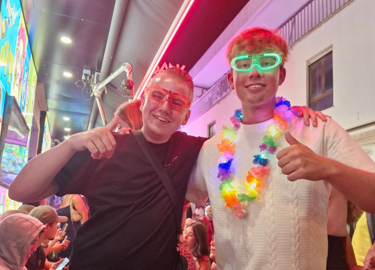 Buitenhof Reizen voor mensen met een verstandelijke beperking - Jongeren - Feest in Lloret - Twee reizigers met lichtgevende brillen in de barstraat