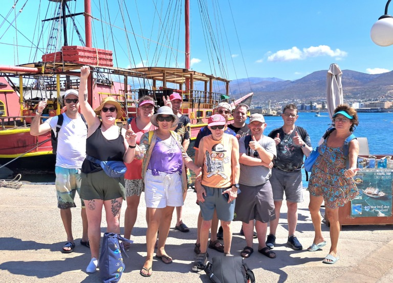 Buitenhof Reizen voor mensen met een verstandelijke beperking - Ondernemend - Grieks genieten op Kreta - reizigers met armen in de lucht voor de boot