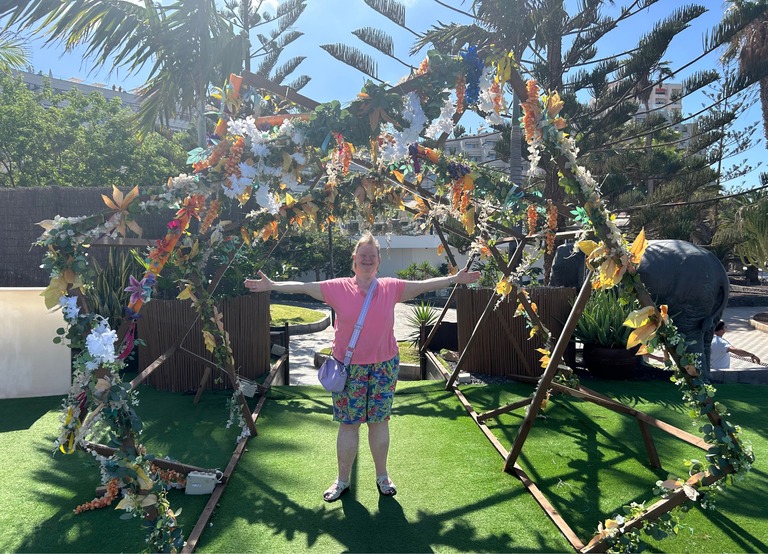 Buitenhof Reizen - Begeleide groepsreizen voor mensen met een verstandelijke beperking - Tenerife - reiziger onder bloemenkunstwerk 