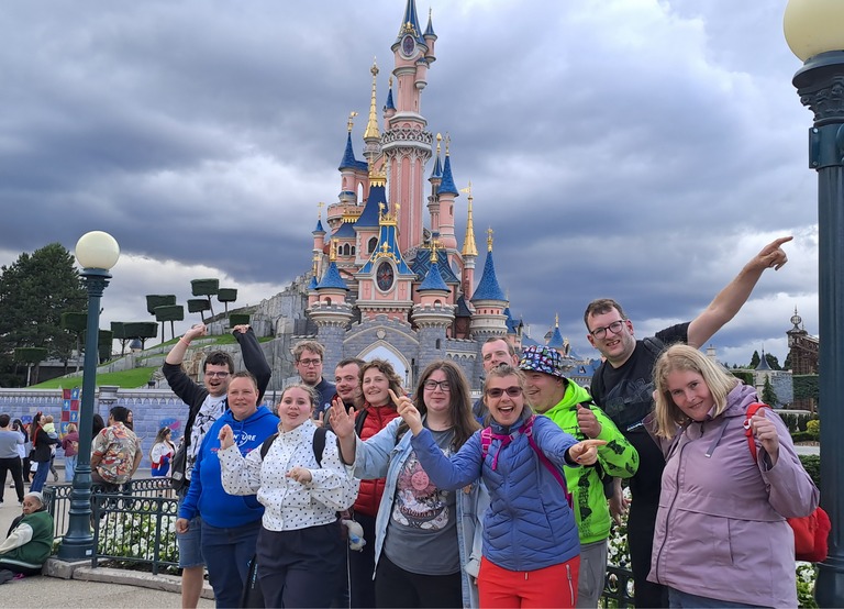 Buitenhof Reizen - Begeleide groepsreizen voor mensen met een verstandelijke beperking - Disneyland Parijs - groep met roze kasteel op achtergrond 